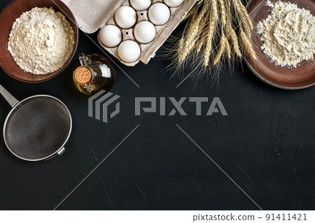 Preparation cooking baking kitchen table brown dishes ware fresh grocery different ingredients: eggs, flour, oil, stuff top view 91411421