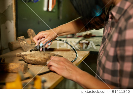 Female using power wood working tools graver, carving while crafting Female using power wood working tools graver, carving while crafting 91411840