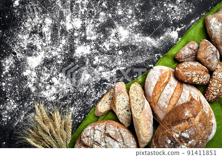 Different bread with flour and spikelets of wheaton black background Different bread with flour and spikelets of wheaton black background 91411851