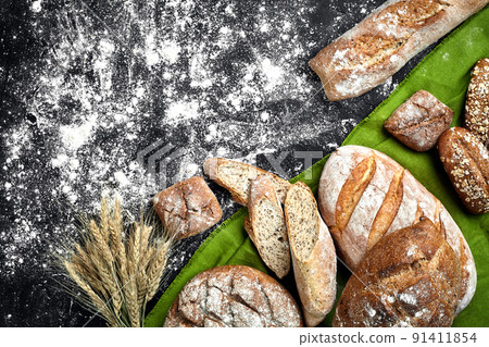 Different bread with flour and spikelets of wheaton black background Different bread with flour and spikelets of wheaton black background 91411854