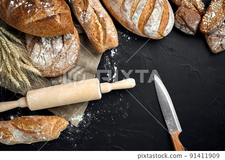 Different bread with flour and spikelets of wheaton black background 91411909