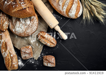 Bakery - gold rustic crusty loaves of bread and buns on black chalkboard background. Bakery - gold rustic crusty loaves of bread and buns on black chalkboard background. 91411919