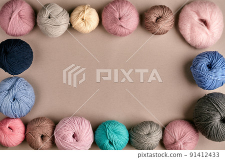 Set of colorful wool yarn on beige background. Top view. Frame of tangles of knitting threads 91412433