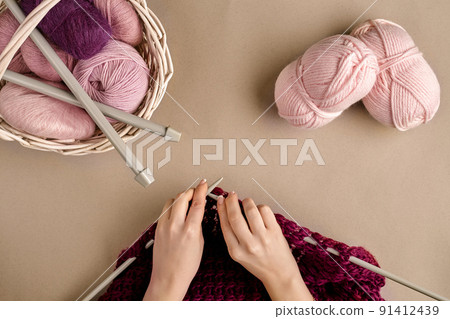 Close-up of female hands knitting wool sweater or plaid lilac color. Top view 91412439