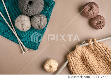 Grey and brown knitting wool and knitting on knitting needles on beige background. Top view. Copy space 91412468