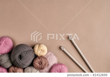 A group of colored balls of yarn and knitting needles on a beige background A group of colored balls of yarn and knitting needles on a beige background 91412600