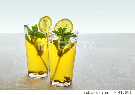 Two glass cups of homemade fermented kombucha tea are decorated with mint and lemon 91412891