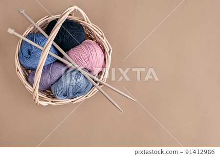 Different colored yarn in basket with knitting needles. Top view 91412986