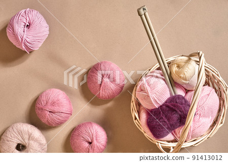 Yarn balls. Balls of colored yarn in a wicker dish. Yarn for knitting on a beige background. Knitting as a kind of needlework. Knitting needles and multi-colored yarn look bright. Yarn balls. Balls of colored yarn in a wicker dish. Yarn for knitting on a beige background. Knitting as a kind of needlework. Knitting needles and multi-colored yarn look bright. 91413012