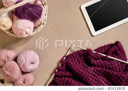 Balls of merino wool yarn, knitting on knitting needles on a beige surface. Top view 91413019