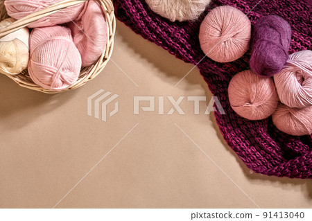 Balls of yarn and knitting needles. Colored yarn for knitting in a wicker bowl on a beige background. Balls of yarn and knitting needles. Colored yarn for knitting in a wicker bowl on a beige background. 91413040