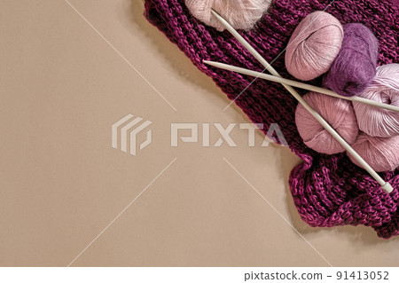 A group of colored balls of yarn and knitting needles on a beige background A group of colored balls of yarn and knitting needles on a beige background 91413052
