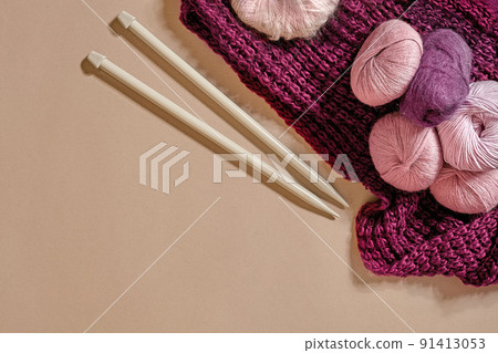 A group of colored balls of yarn and knitting needles on a beige background A group of colored balls of yarn and knitting needles on a beige background 91413053