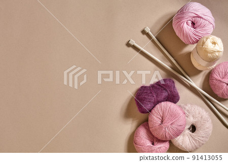 A group of colored balls of yarn and knitting needles on a beige background A group of colored balls of yarn and knitting needles on a beige background 91413055