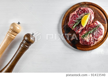 Raw beef steak with spices and ingredients for cooking on wooden cutting board and white background. 91413540