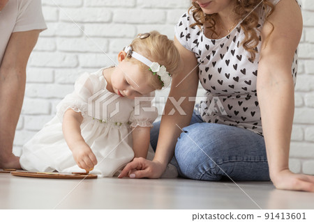 Child girl with cochlear implant plays at home with mother and father. Hear impairment and diversity and hearing aid Child girl with cochlear implant plays at home with mother and father. Hear impairment and diversity and hearing aid 91413601