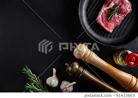 Fresh raw meat. Beef Tenderloin and marbled beef steaks on grill pan and frying board with seasoning, black background top view. 91413603