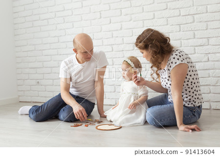 Child girl with cochlear implant plays at home with mother and father. Hear impairment and diversity and hearing aid Child girl with cochlear implant plays at home with mother and father. Hear impairment and diversity and hearing aid 91413604