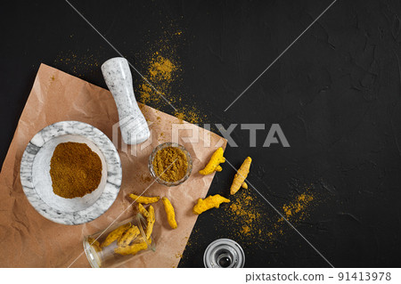 Turmeric Haldi powder in small bowl with raw whole in marble mortar over black background with copy space Turmeric Haldi powder in small bowl with raw whole in marble mortar over black background with copy space 91413978