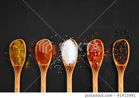 Various spices in wooden spoons on black table Various spices in wooden spoons on black table 91413991