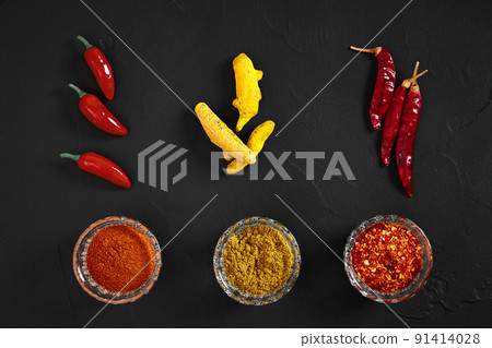 Cooking using fresh ground spices with three small bowls of spice on a black table overhead view with copyspace 91414028