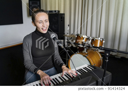 Young Japanese or European woman singing song on mic, playing electronic piano 91414324