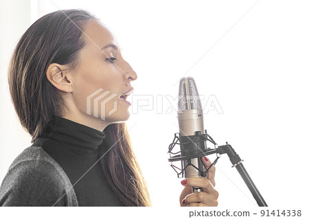 Young Caucasian woman singing or speaking to mic in music or radio studio 91414338