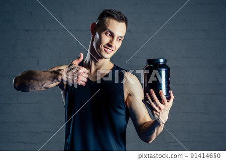 a young man holding a jar of protein in the gym 91414650