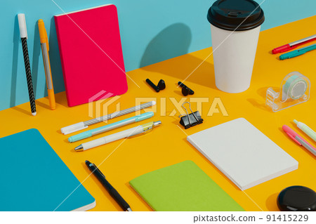 Colorful notepads, pens and paper cup on orange table Colorful notepads, pens and paper cup on orange table 91415229