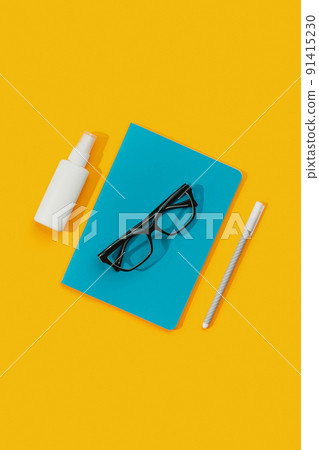 Notepad Glasses Pen and Sanitizer Against an Orange Background. Notepad Glasses Pen and Sanitizer Against an Orange Background. 91415230