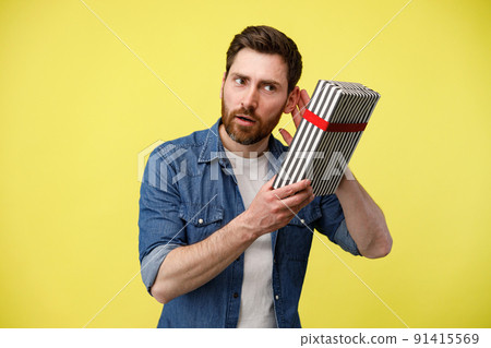 Portrait of interested guy listening what rattles In gift box. Guess What's Inside Portrait of interested guy listening what rattles In gift box. Guess What's Inside 91415569