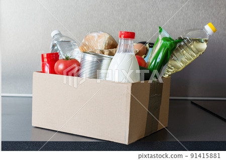 Various food, bottle of oil, milk and water, fresh vegetables in a cardboard box. Food donations or food safe delivery concept. 91415881