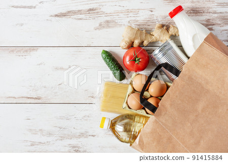 Paper shopping bag with various food top view on white wooden background. Food donation, safe delivery service concept. 91415884