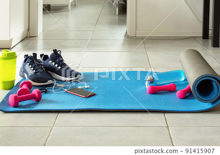 Fitness sports equipment and smartphone on the floor in living room. Home online workout concept. 91415907