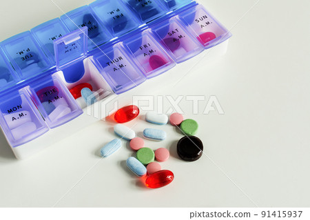 Pills and vitamins in a pill box organizer on white table. Pills and vitamins in a pill box organizer on white table. 91415937