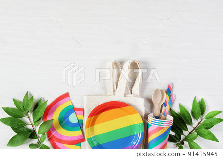 Rainbow colored disposable dishes on white wooden background top view. Birthday party eco friendly dishes,picnic utensil. 91415945