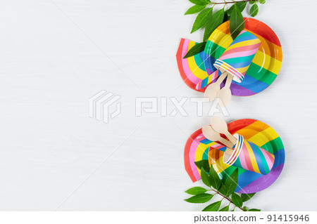 Rainbow colored disposable dishes on white wooden background top view. Birthday party eco friendly dishes,picnic utensil. Rainbow colored disposable dishes on white wooden background top view. Birthday party eco friendly dishes,picnic utensil. 91415946