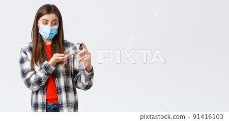 Coronavirus outbreak, leisure on quarantine, social distancing and emotions concept. Cute woman taking care of health doing preventing measures, apply hand sanitizer, wear medical mask 91416103
