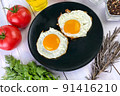 Fried eggs with vegetables, spices and herbs on light wooden background. Traditional European or Asian breakfast. 91416210