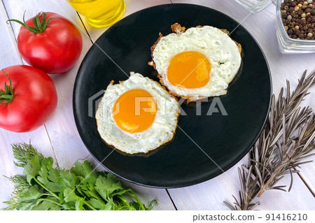 Fried eggs with vegetables, spices and herbs on light wooden background. Traditional European or Asian breakfast. Fried eggs with vegetables, spices and herbs on light wooden background. Traditional European or Asian breakfast. 91416210