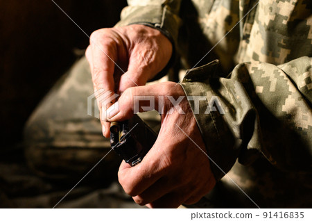Filling the magazine with combat military assault rifles AK 74, a soldier in a trench holding ammunition for a machine gun. 91416835