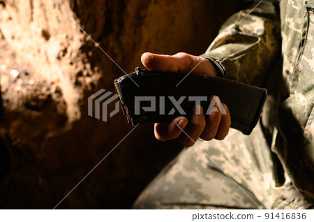 Filling the magazine with combat military assault rifles AK 74, a soldier in a trench holding ammunition for a machine gun. 91416836