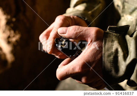 Filling the magazine with combat military assault rifles AK 74, a soldier in a trench holding ammunition for a machine gun. 91416837