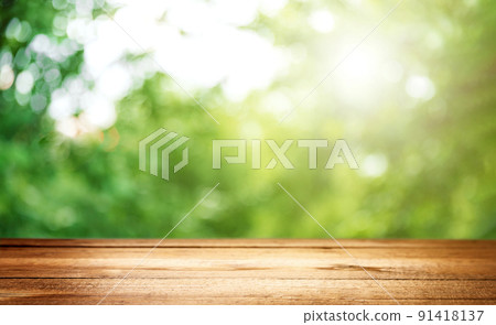 Blank country fence plank, table top or counter bar with abstract green forest trees background. Nature bokeh sunlight. Mock up, product template. Banner or header for advertise on social media 91418137