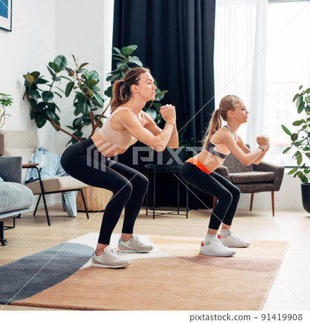 Mother and daughter doing squats. Home training 91419908