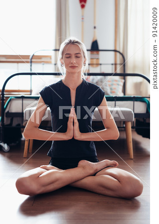 Woman doing yoga exercise at home . Fit woman meditating in lotus pose. Woman doing yoga exercise at home . Fit woman meditating in lotus pose. 91420009