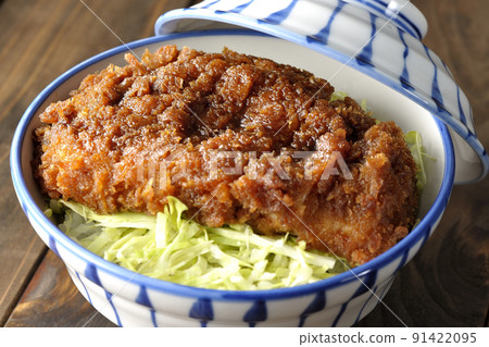 Sauce and bowl with cutlet entwined with plenty of sauce on top of shredded cabbage 91422095
