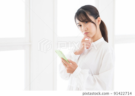Thinking of a woman watching a smartphone in a room 91422714