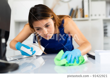 Woman cleaning desk in office Woman cleaning desk in office 91422921