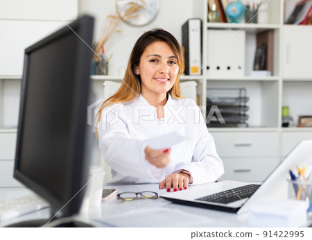 Mexican woman doctor in uniform is giving recipe to client 91422995